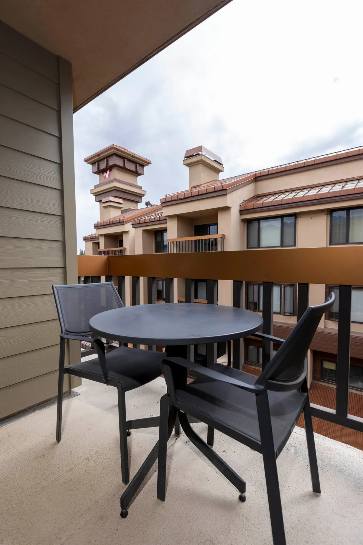 A serene balcony scene featuring comfortable furniture, inviting guests to relax with coffee or tea while taking in the sunset and the surrounding architecture of the village.